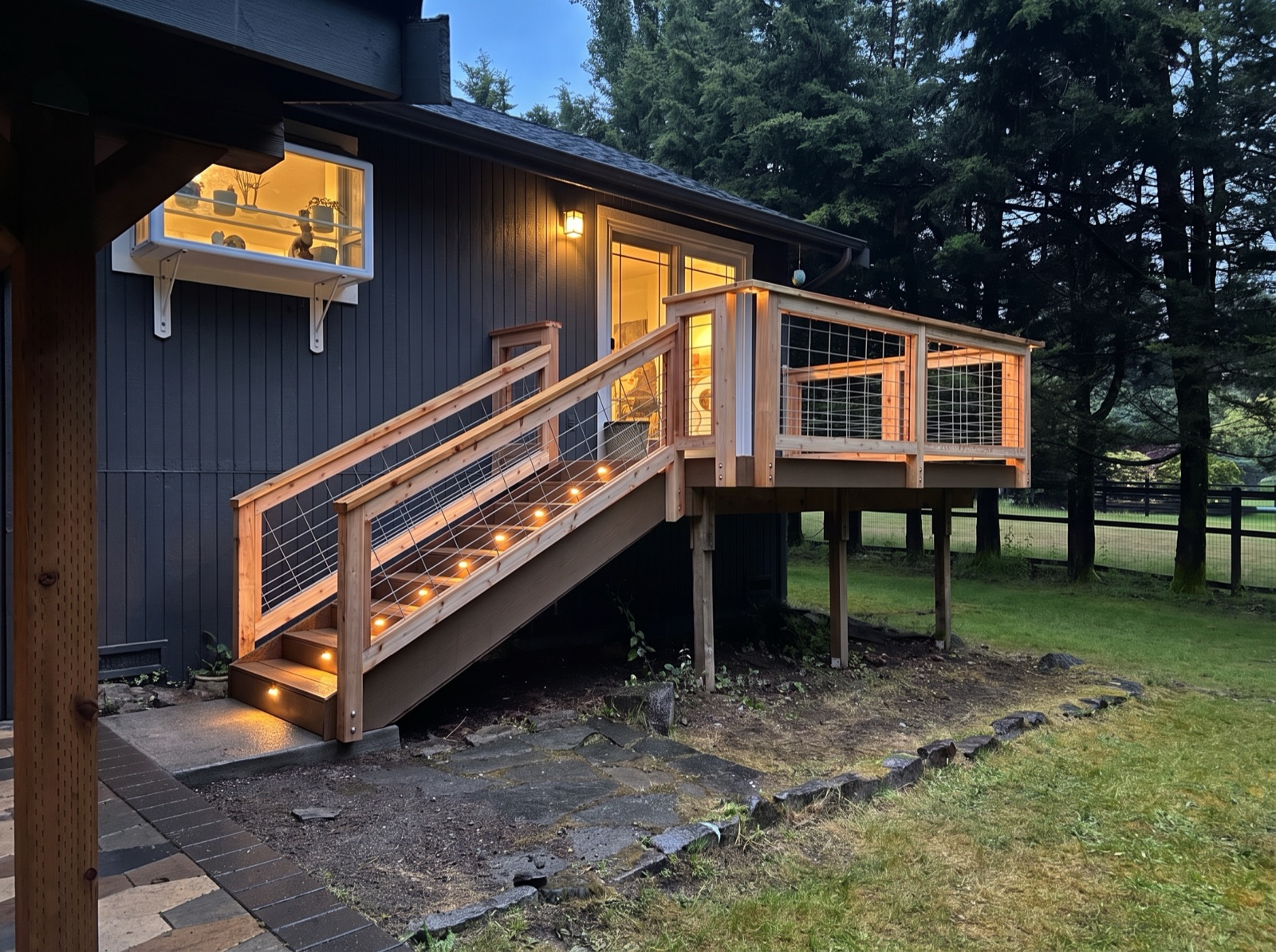 Stellar Decking cedar deck and staircase lit with warm integrated lighting at dusk